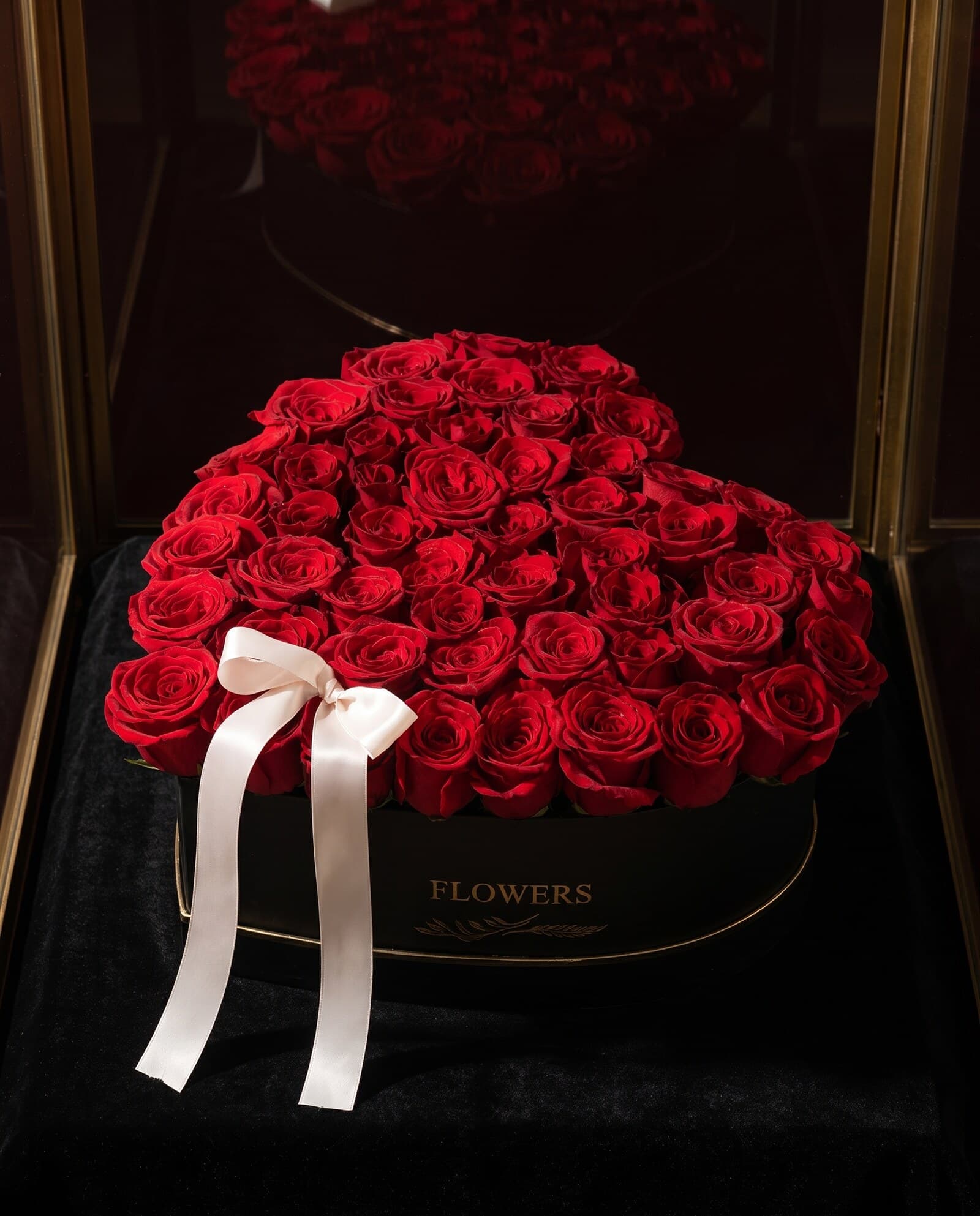 A generous arrangement of red roses in a hat box